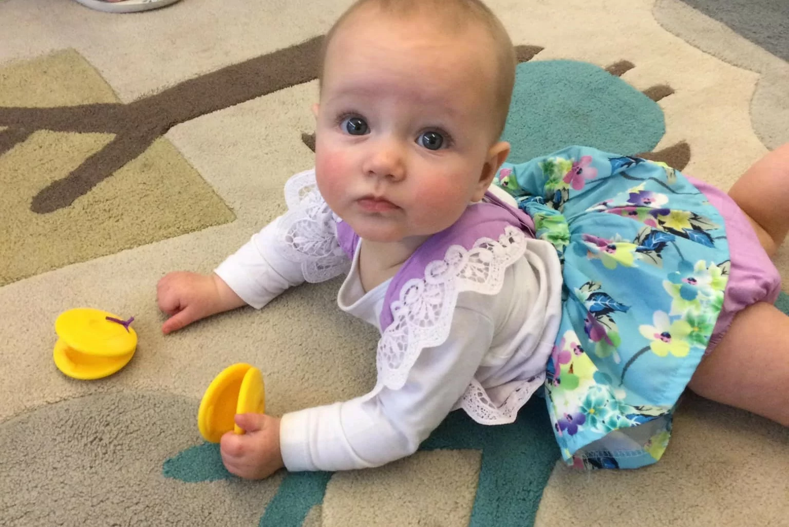 Baby lying on the floor holding maracas