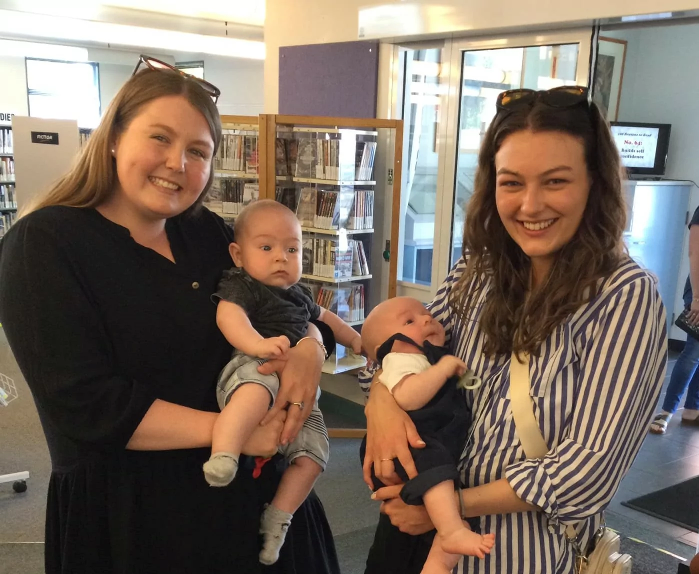 Two women holding babies in the library