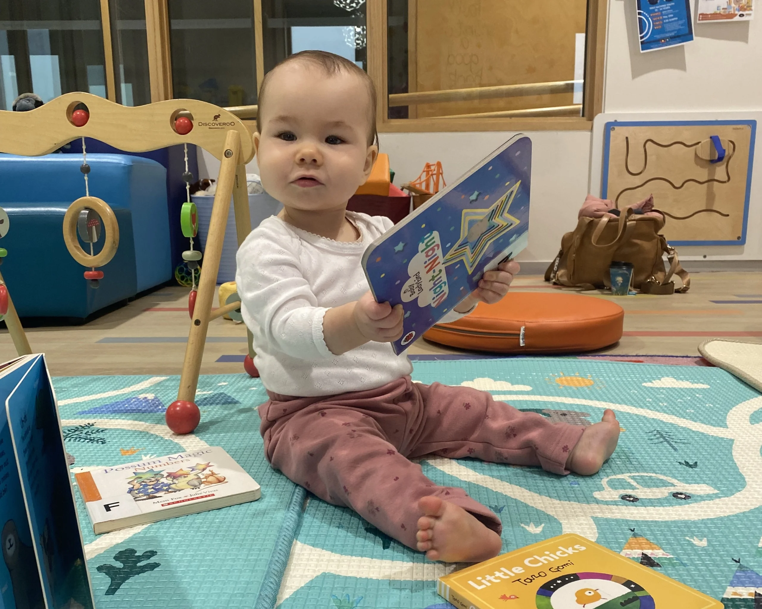 Baby on a mat holding a baby book