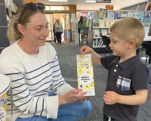 A mother and her boy donate money to the Biggest Morning Tea