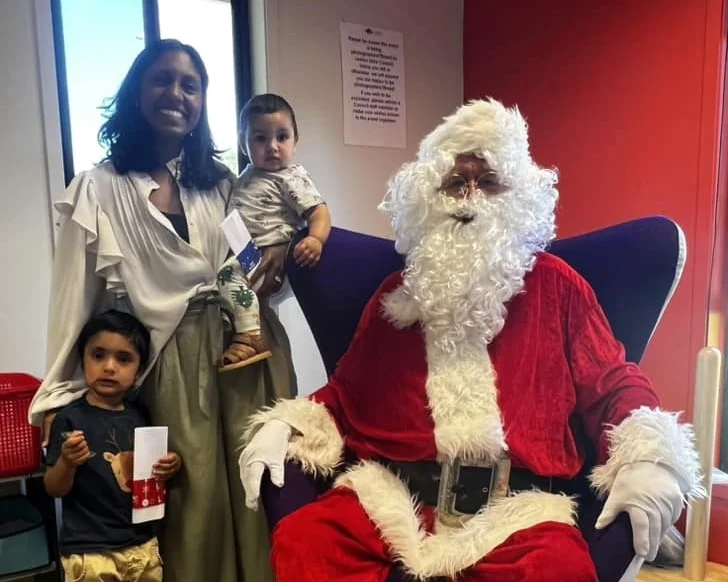 A family with a baby poses with Santa at the library