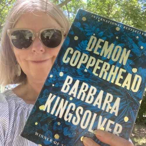 A library staff member displays the book Demon Copperhead by Barbara Kingsolver