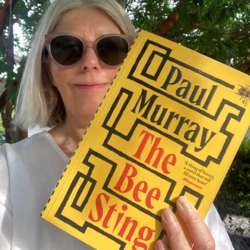 A library staff member holds up a copy of The Bee Sting by Paul Murray