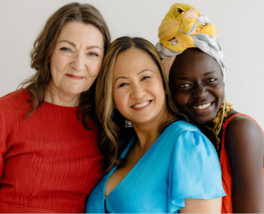 Three business women pose together in a huddle