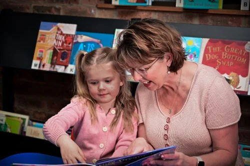 Image of a young grandparent reading with her young grandchild at the library.