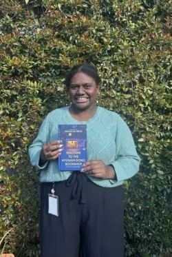 Heidi Robinson from Bland Shire Library holds up Welcome to the Hyunam-dong Bookshop by Hwang Bo-reum