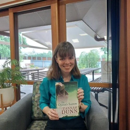 A library staff member poses with The Queen's Sorrow by Suzannah Dunn