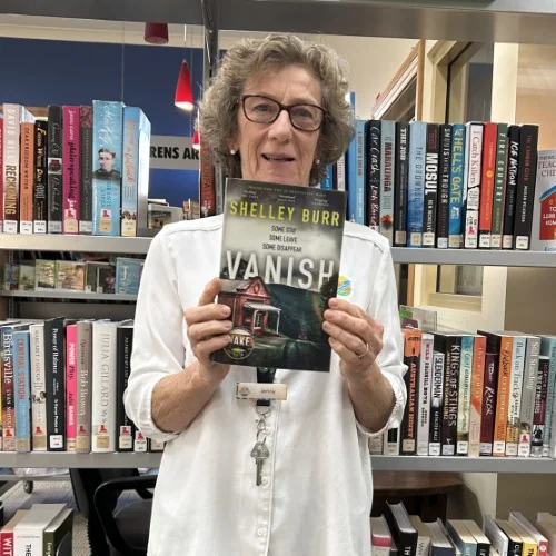 A library staff member holds up a copy of Vanish by Shelley Burr