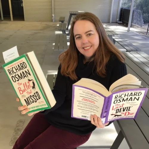 A library staff member reads The Bullet that Missed and The Last Devil to Die by Richard Osman