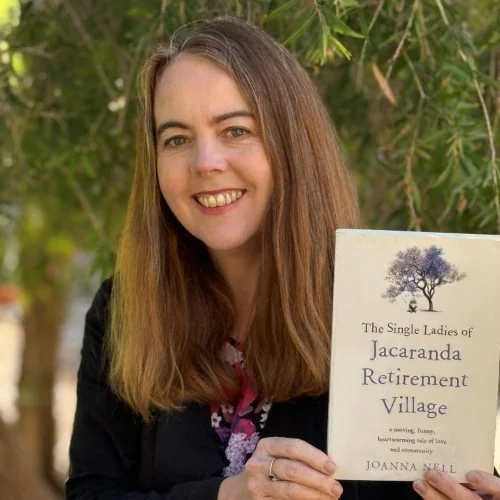 A library staff member displays the book, The Single Ladies of Jacaranda Retirement Village by Joanna Nell