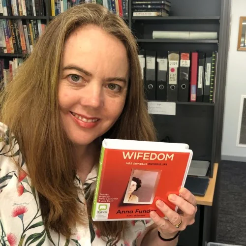 Library staff holding the audiobook of Wifedom by Anna Funder