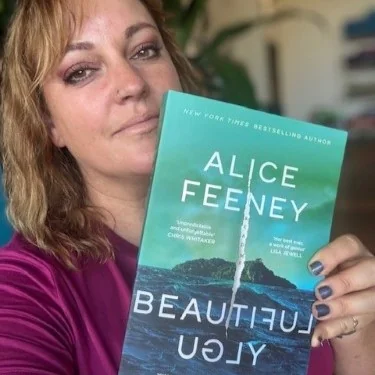 A library staff member hold up the book Beautiful Ugly by Alice Feeney.