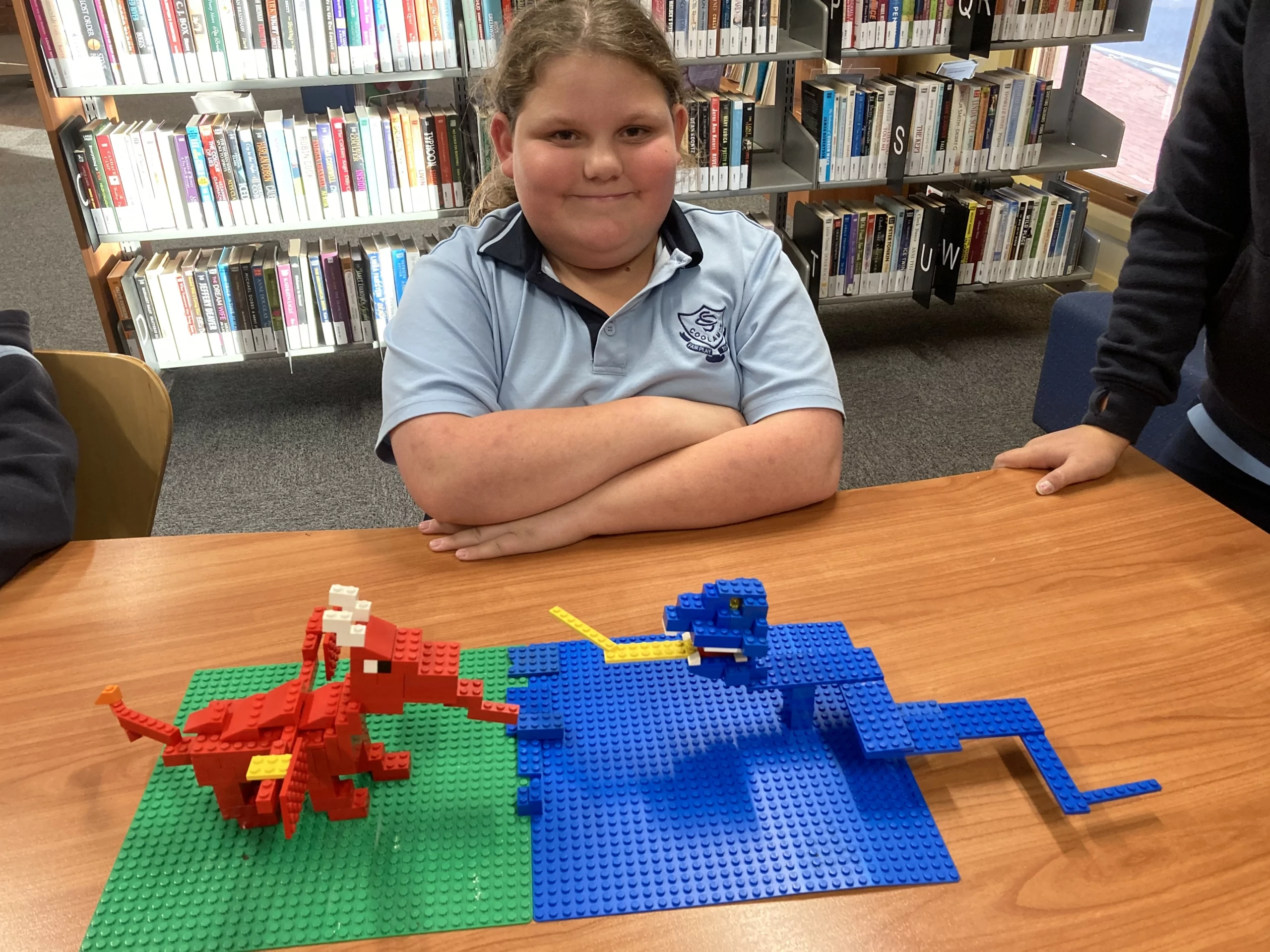 Child poses with her Lego creations, two dragons