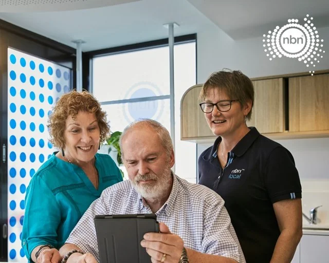 An NBN staff member helps a man learn about online safety on his tablet