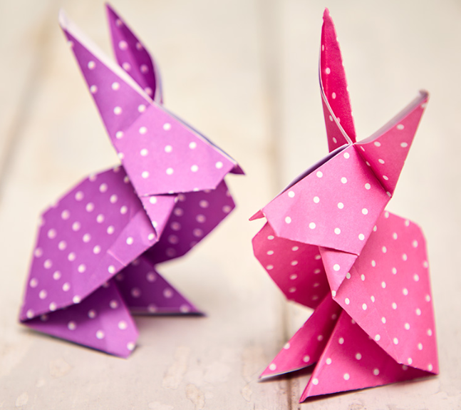 Origami bunnies made from bright pink and purple paper with white spots.