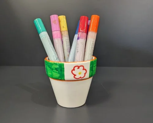 Image of a painted terracotta pot holding paint pens