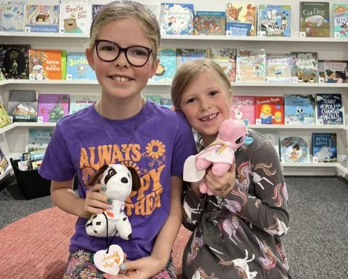 Two girls holding cute stuffed puppies and unicorns