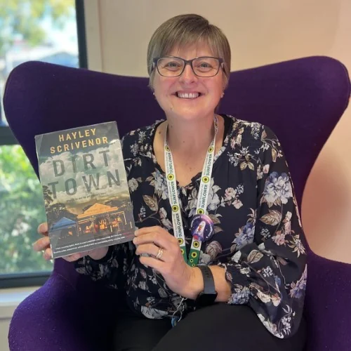 A library staff member displays the book Dirt Town by Hayley Scrivenor