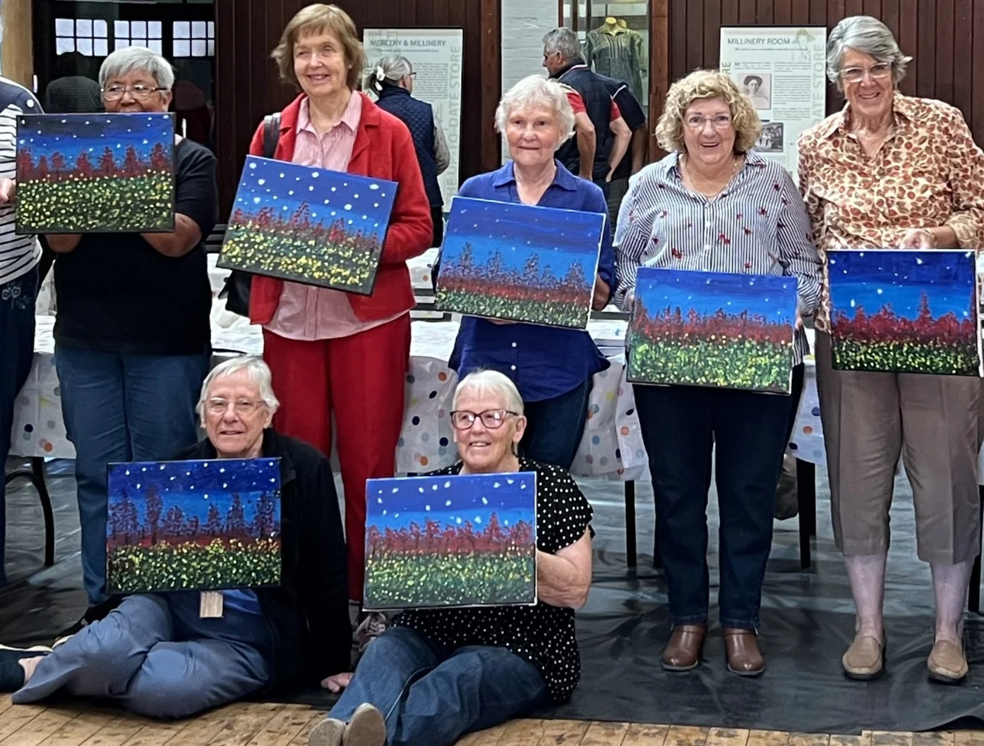 Image of seniors holding up finished canvas artworks