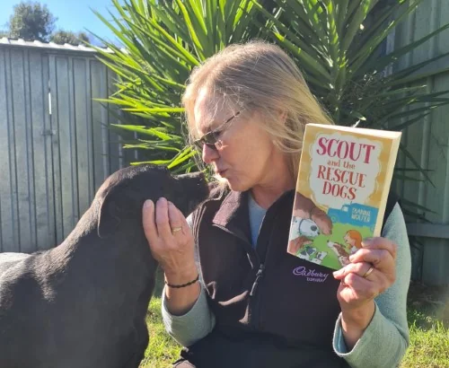 Library staff poses with Scout and the Rescue Dogs while patting her own dog