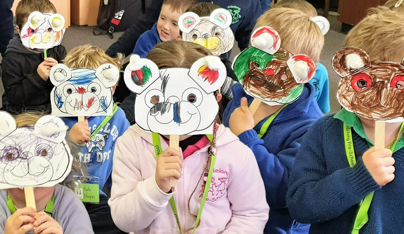 Children holding painted paper masks over their faces