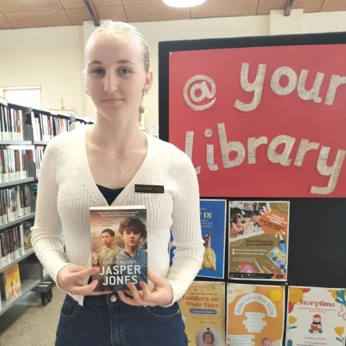 A library work experience student poses with Jasper Jones in the library