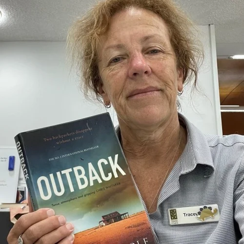 A library staff member displays the book Outback by Patricia Wolf