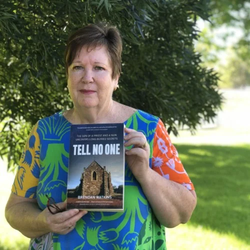 A library staff member displays the book Tell No One by Brendan Watkins