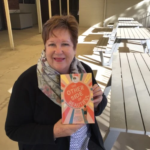 A library staff member displays The Other Side of Beautiful by Kim Lock