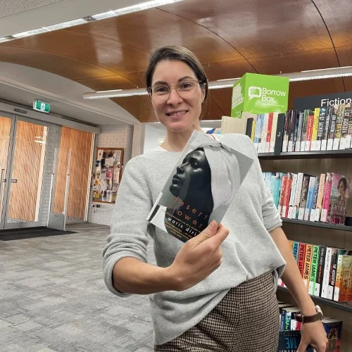 A librarian holds up a copy of Desert Flower by Waris Dirie