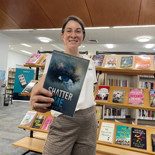 A library staff member holds up Shatter Me by Tahereh Mafi