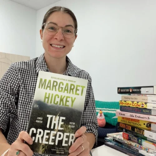 A library staff member holds up The Creeper by Margaret Hickey in the library.